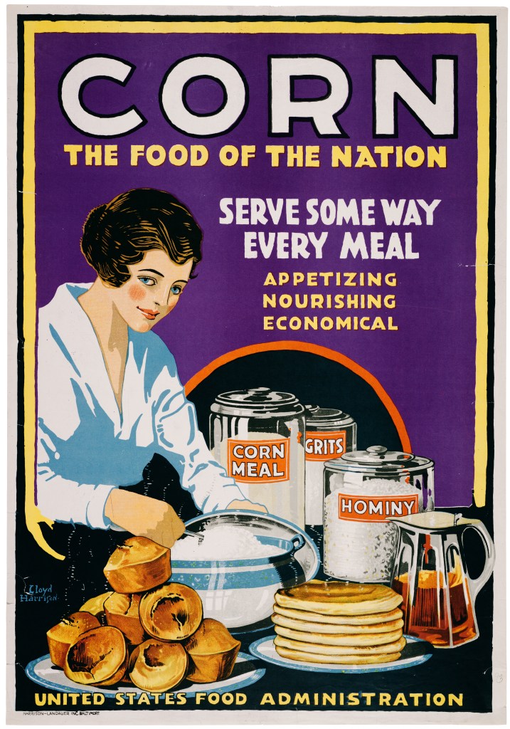 "Corn. The Food of the Nation. Serve some way every meal. Appetizing, nourishing, economical." A woman stands over a table loaded with muffins, pancakes, and cannisters of corn meal, grits, and hominy.